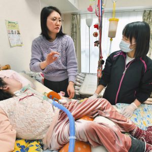 写真は診療に訪れた岡野恵里香医師（右）と華子さん（手前）の様子について話す母の福満美穂子さん＝東京都中野区で