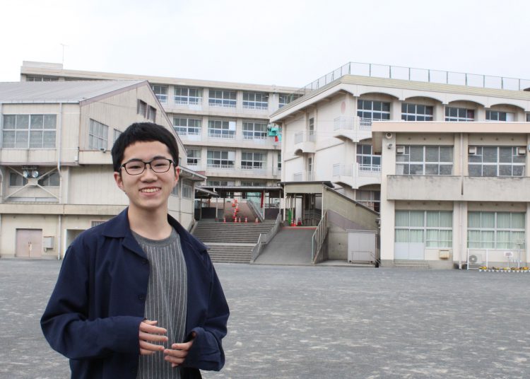 母校の小学校の前でエアコン設置を求めた活動について話す今田恭太さん＝静岡県富士市で
