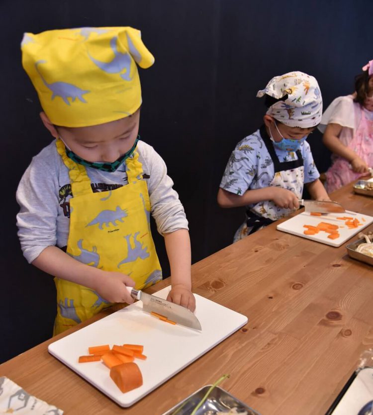 料理教室で包丁を使って野菜を切る子どもたち
